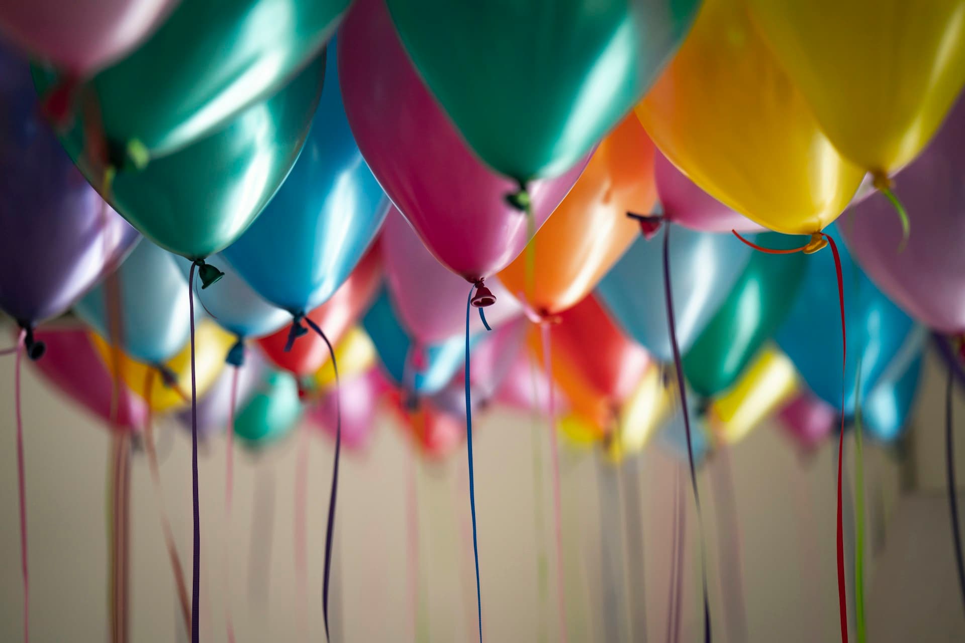 A ceiling of colourful party balloons with ribbons hanging down