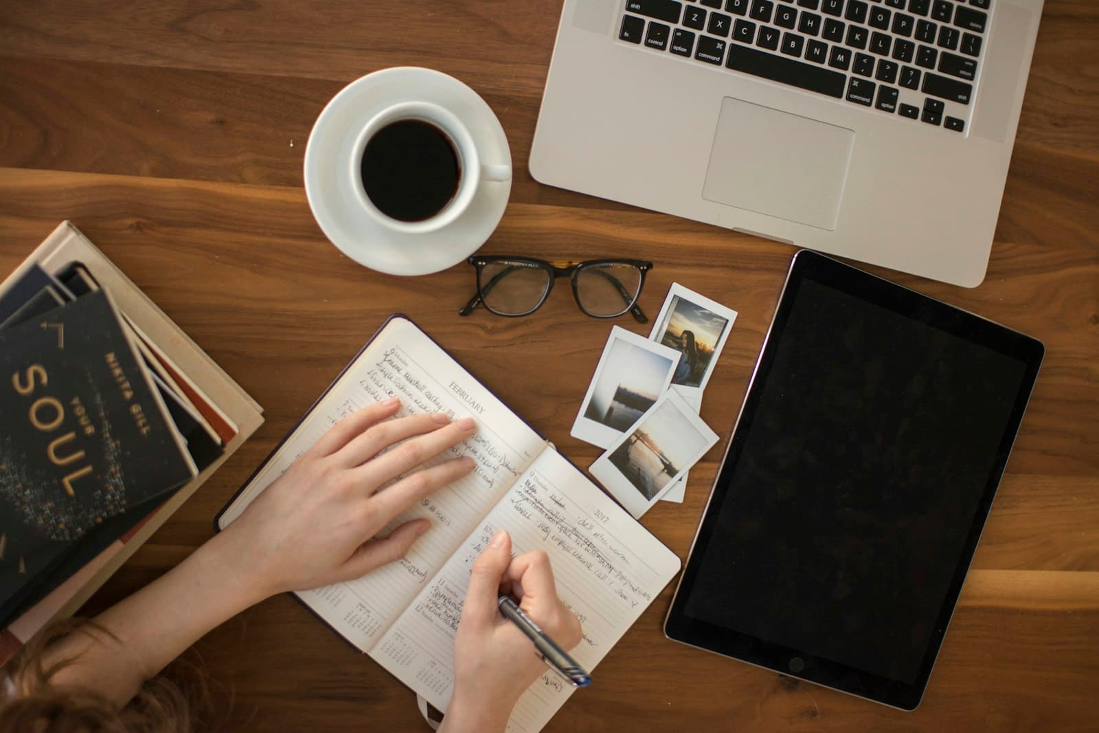 A study desk seen from above with a notebook, laptop and coffee
